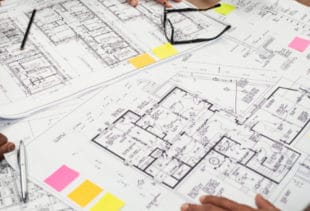 Image d'illustration représentant une table vue de haut où des plans d'appartements et de maisons sont entreposés
