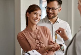 Image d'illustration représentant un couple souriant recevant des clés d'appartement de la part d'un promoteur immobilier