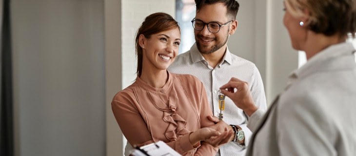 Image d'illustration représentant un couple souriant recevant des clés d'appartement de la part d'un promoteur immobilier