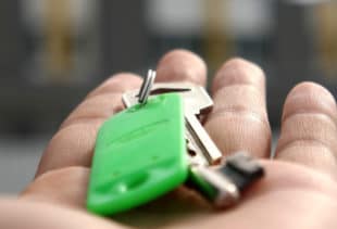 Image d'illustration représentant une main ouverte et tendue vers l'avant avec un trousseau de clés et un porte-clés vert