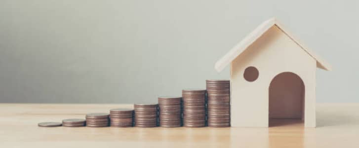 Image d'illustration représentant des empilements de pièces de monnaie et une petite maison en bois