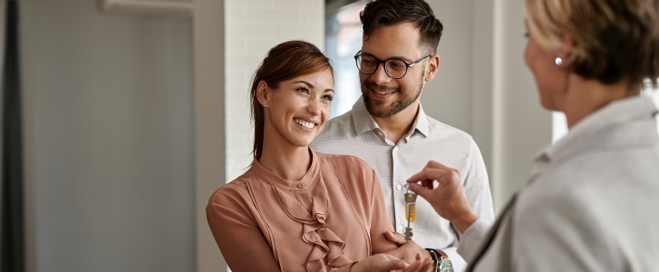 Image d'illustration représentant un couple souriant recevant des clés d'appartement de la part d'un promoteur immobilier